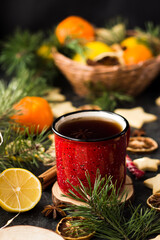 hot tea in a red mug in a new year's atmosphere. Christmas morning. A mug with a drink next to Christmas tree branches, oranges, spices and cookies