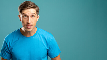 Fototapeta premium Angry male portrait. Critical abusing. Aggressive emotion. Young expressive man looking at camera offending isolated on blue copy space.