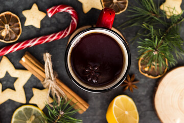 hot tea in a red mug in a new year's atmosphere. Christmas morning. A mug with a drink next to Christmas tree branches, oranges, spices and cookies