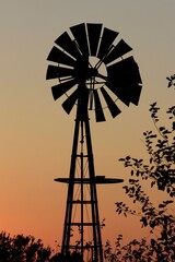 silhouette of windmill at Sunset with tree's and sky north of Hutchinson Kansas USA out in the country.