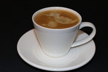 Cup of coffee in a white cup on a saucer on a black background