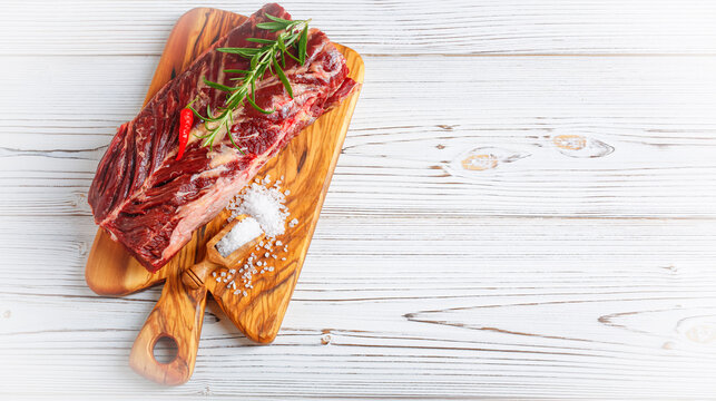 Fresh raw flank steak on the very nice rustikal wooden plate. White background with copy space for text.