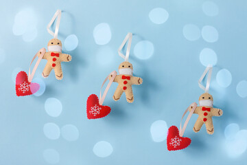 Pattern of Gingerbread men in a protective mask with a Christmas tree shaped heart ornament christmas tree is on a blue background with bokeh lights. The concept of a creative Christmas and new year.
