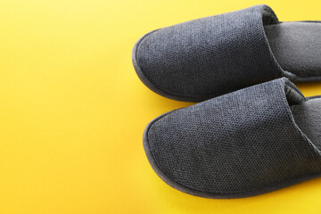 Gray home slippers on a yellow paper background. Clear warm domestic sandal or sneakers. Bed shoes accessory footwear.View from above. Copy space