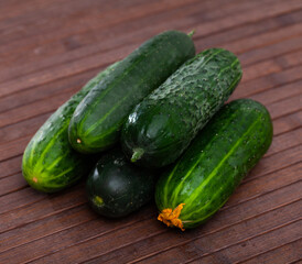 Many ripe juicy cucumbers on wooden surface closeup