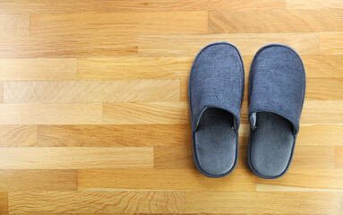 Gray home slippers on the parquet floor. View from above.Clear warm domestic sandal or sneakers. Bed shoes accessory footwear. Copy space