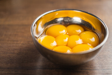 Ingredients in containers for baking, making a cake, or other desserts. Raw separated egg yolks on a wood table top.