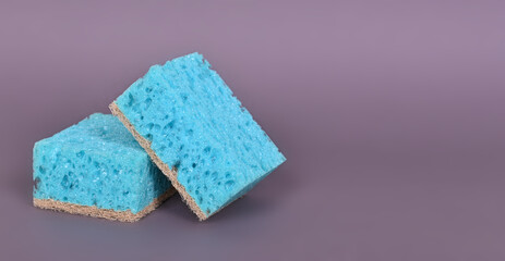 A porous blue washcloth for cleaning the apartment and washing dishes on a gray background.