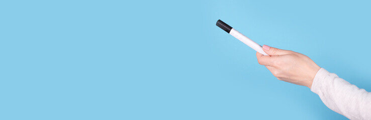 Black marker in hand on a blue background, copy space template, banner.