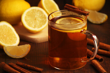 A mug with hot tea with lemons and cinnamon sticks