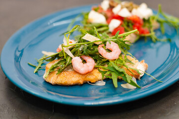 Bruschetta with shrimp, arugula, tomatoes, cheese and sauce, closeup, on gray background, high Italian cuisine
