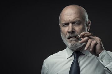 Confident senior business executive smoking a cigar