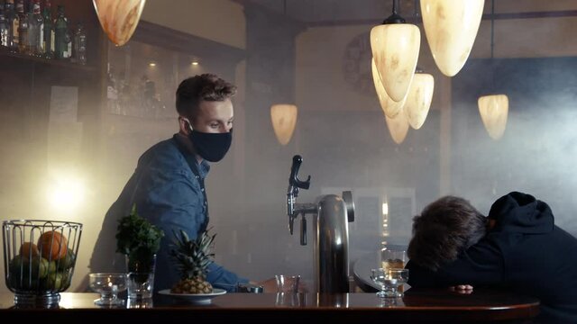 Barkeeper wearing face mask and an apron cleaning up the smoky bar and wake up customer shot in 4k