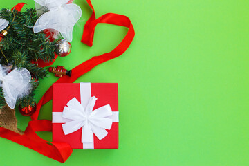 Christmas composition. Christmas gift, presrnt box,red ribbon and fir tree branches with toys. Top view, flat lay.