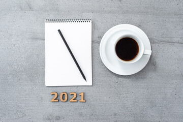 New year 2021. Flat lay of office space with coffee cup, notepad, pencil and wooden numbers.