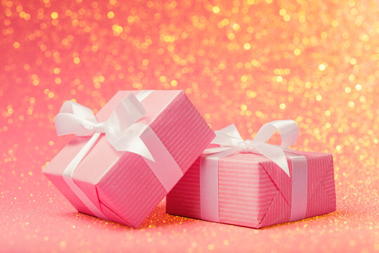 Alike pink gift boxes over holiday background with defocused lights and copy space