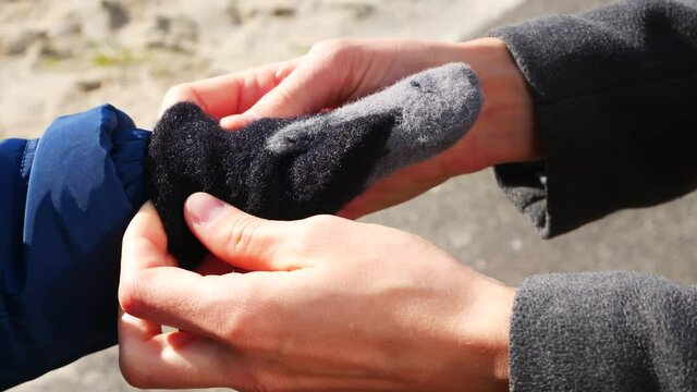 A woman puts a warm mitten on a childs hand