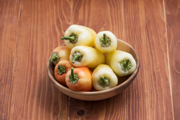 Fresh raw peppers in a wooden bowl. Ripe orange-red peppers. Close up. Copy space.