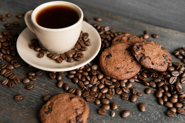 Coffee cup with cookies on wooden table background. Mug of black coffee with scattered coffee beans...