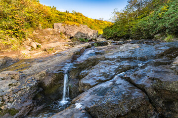 栗駒山紅葉の季節の渓流を横切る登山道
