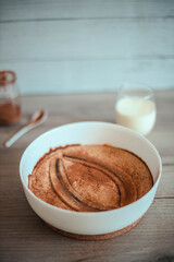 Fresh banana pie in a white dish on a wooden board. Homemade cheesecake with banana chunks and cinnamon.