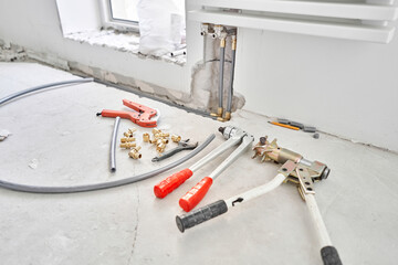 Tools for Work As A Plumber. Connection heating pipes to white Radiator in a new apartment under construction. water heating radiator on the white wall indoors
