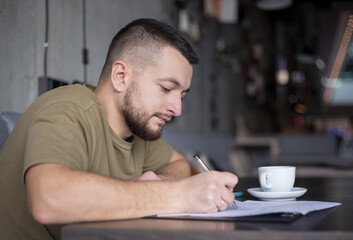 business, education and people concept - young man with coffee writing at cafe.