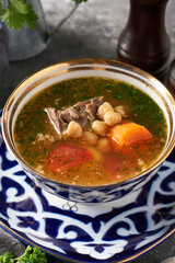 Traditional asian shurpa soup in traditional ornament bowl on ray background