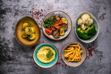 different side dishes on a grey background, French fries, mashed potatoes, rice, vegetables, top view