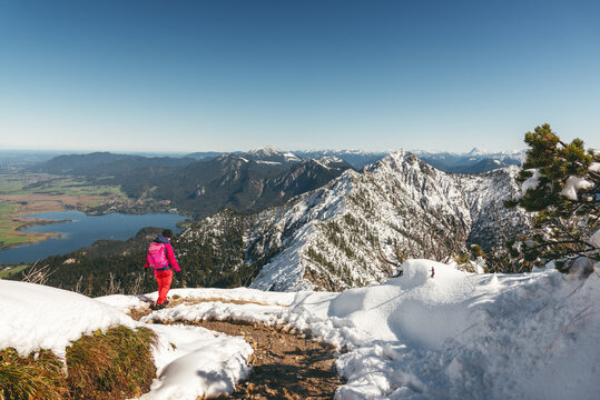 Wanderin im Neuschnee auf dem Gratweg zwischen Heimgarten und Herzogstand mit Blick auf den Walchensee