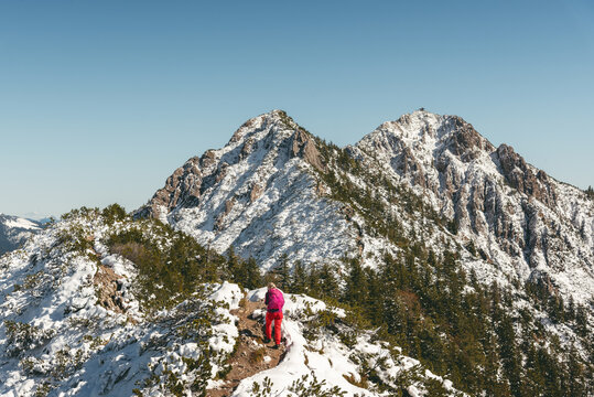 Wanderin im Neuschnee auf dem Gratweg zwischen Heimgarten und Herzogstand mit Herzogstand-Gipfel im Hintergrund