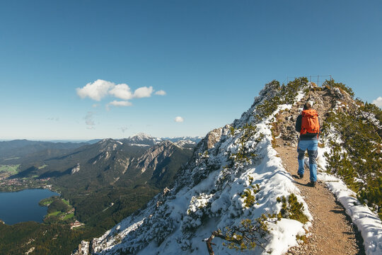 Wanderer im Neuschnee auf dem Gratweg zwischen Heimgarten und Herzogstand mit Blick auf den Kochelsee