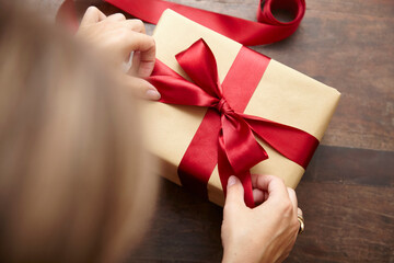 Frau bindet rote Geschenkschleife