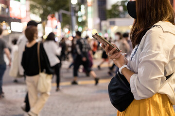 夜の渋谷でスマホを操作する若い女性の手元