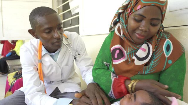 Doctor examining baby in clinic. Africa