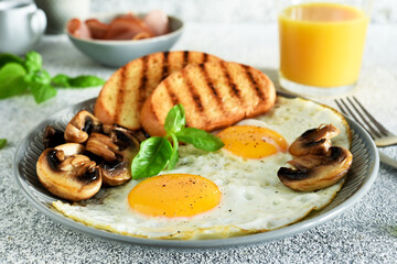 English breakfast. Fried eggs with mushrooms and ham with a glass of orange juice for breakfast. Good morning.