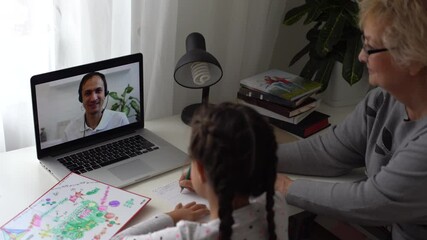 little girl studying with her grandmother at home, use laptop for education, online study, home studying. Girl has homework at distance learning. Lifestyle concept for Family quarantine covid-19.