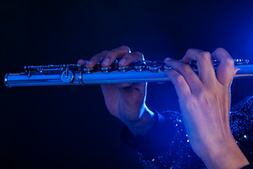 Close up of the hands of a young woman playing a silver flute