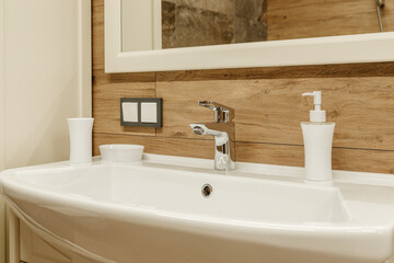 white sink with mirror on wooden tiles background with gray switch on the wall, silver mixer and white stuff