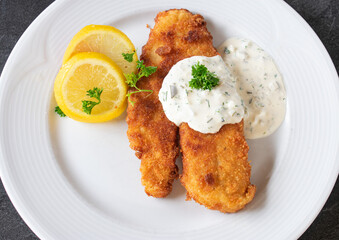 Pan fried fish with remoulade on a white plate - isolated overhead view