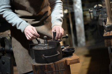 Professional blacksmith working with metal  at forge, workshop. Handmade, craftsmanship and...