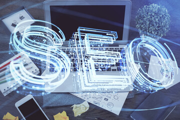 Multi exposure of table with computer and seo drawing hologram. Search optimization concept.