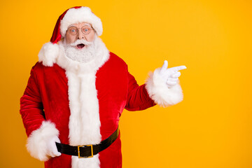 X-mas christmas disocunt here. Santa claus point index finger copyspace demonstrate fairy magic ads promo feel astonished wear cap headwear isolated over bright shine color background