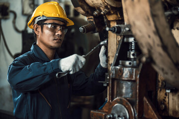 Asian engineer mechanic man checking and using wrench for maintenance pressing metal machine at...