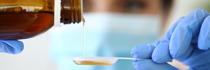 Nurse pouring medicated cold syrup into plastic spoon. Treatment of prostate and bronchial diseases concept