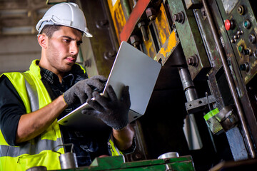 Caucasian engineer mechanic man checking for maintenance pressing metal machine by laptop at...