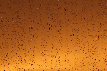 Rain drops on the window glass. Drops of water on window, yellow and orange sunset in background.
