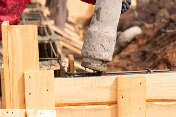 Close up of construction worker laying cement or concrete into the foundation formwork with automatic pump