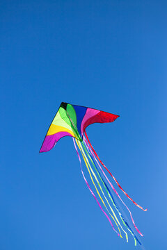 A colorful triangle kite flies under blue sky. sunny autumn.