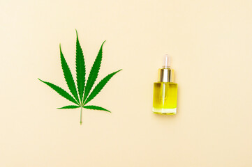 Top view of medical cannabis leaf near CBD oil in bottle on white background. Essential natural oils for face and body.